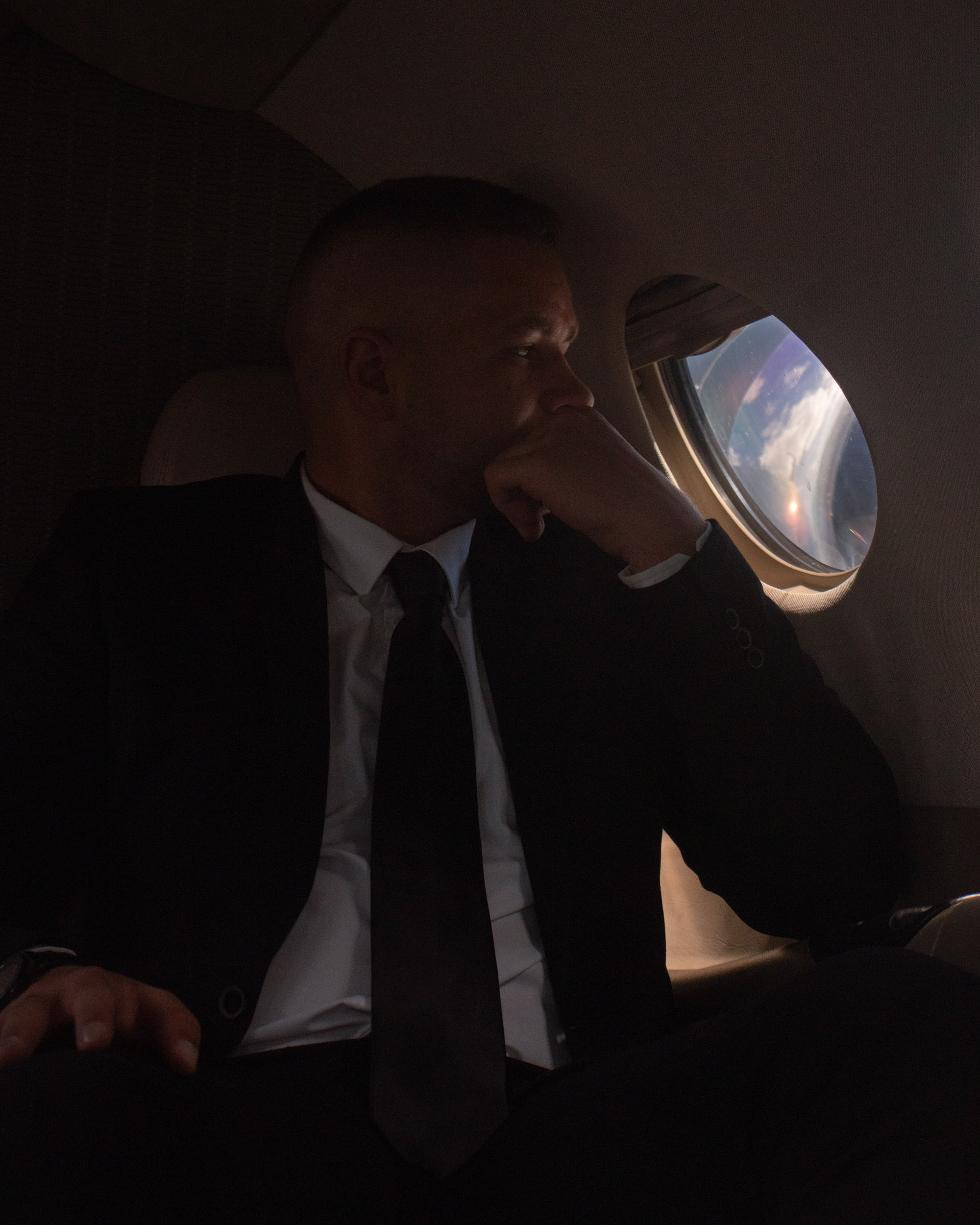 A young man wearing a suit in a plane